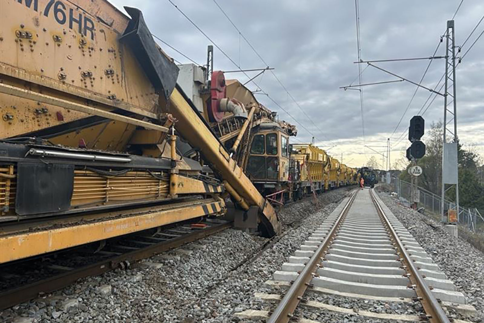 En lang, gul arbeidsmaskin i sving på det venstre av to spor.