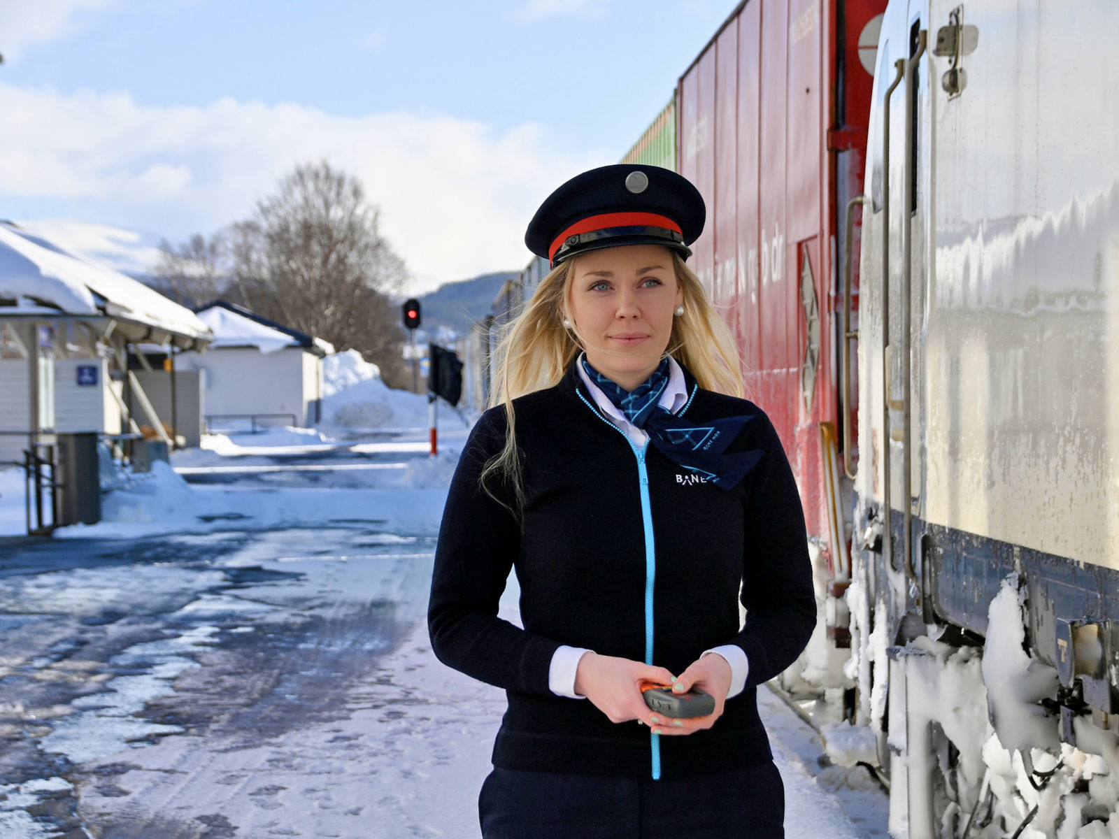 Bilde av ei kvinne i trafikkstyraruniform ved eit tog.