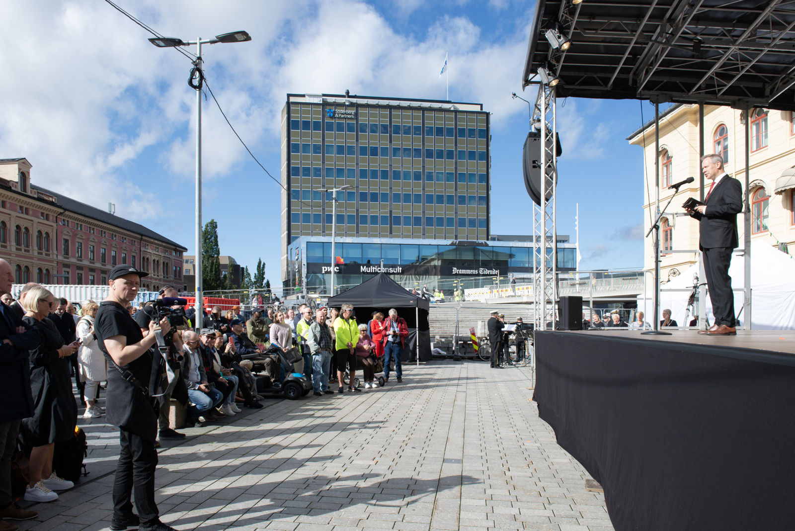 Mann som taler på scene med publikum foran.