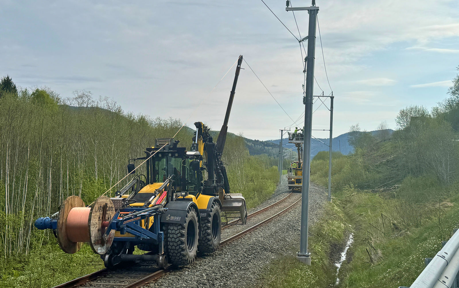 Skinnegående anleggsmaskiner som trekker kontaktledningstråd i Hegra.