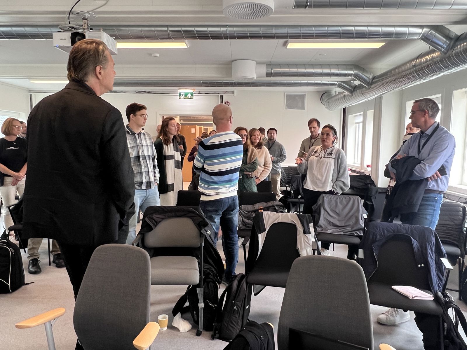 Menn og kvinner står og samtaler