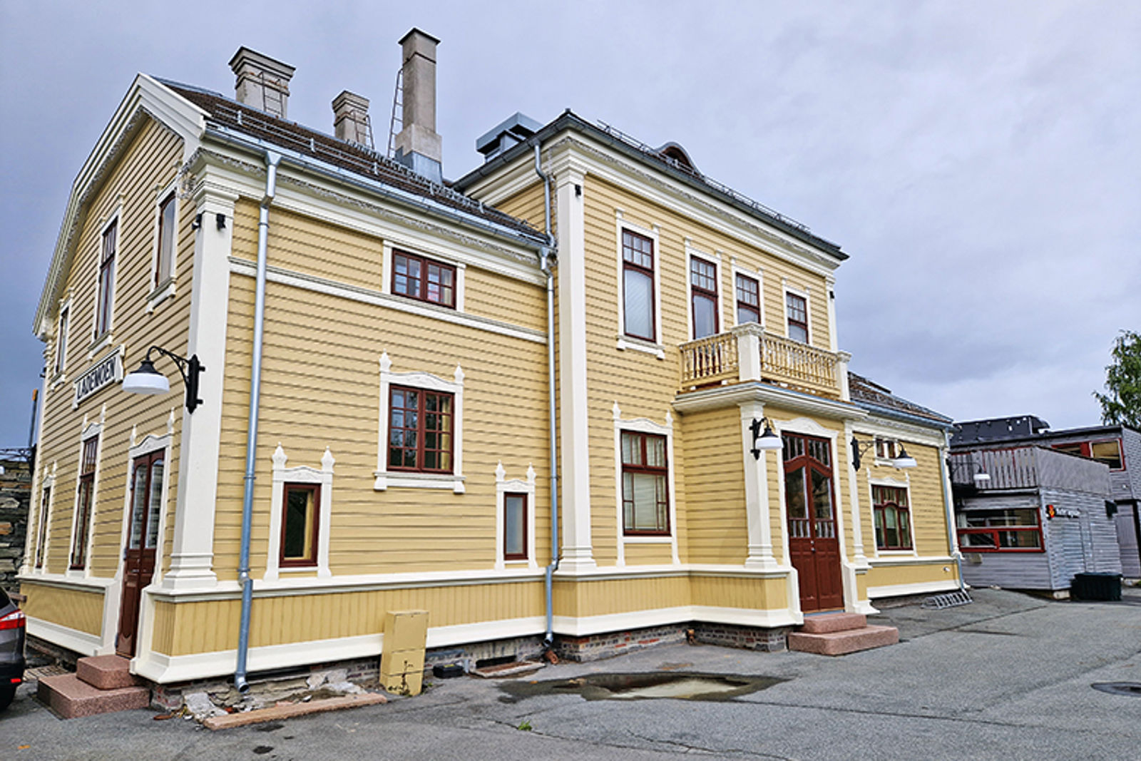 Et toetasjers trehus med veranda over inngangspartiet, og utsmykkede trelister rundt hver av de mange vinduene.